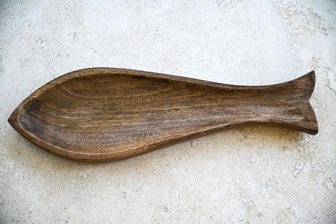 Wooden fish-shaped platter on a textured surface